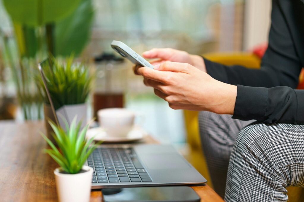Člověk používá mobilní telefon a notebook, na kterých spravuje své online účty a digitální data.
