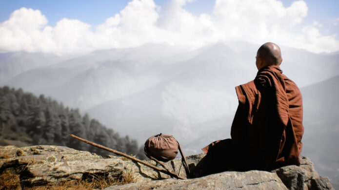 Tibetský buddhistický mnich pozoruje mlhou zahalenou krajinu.